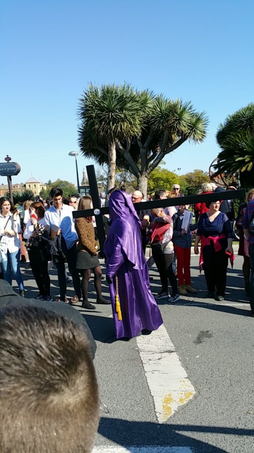 A member of the procession in a traditional capirote carries a crucifix as part of the celebration
