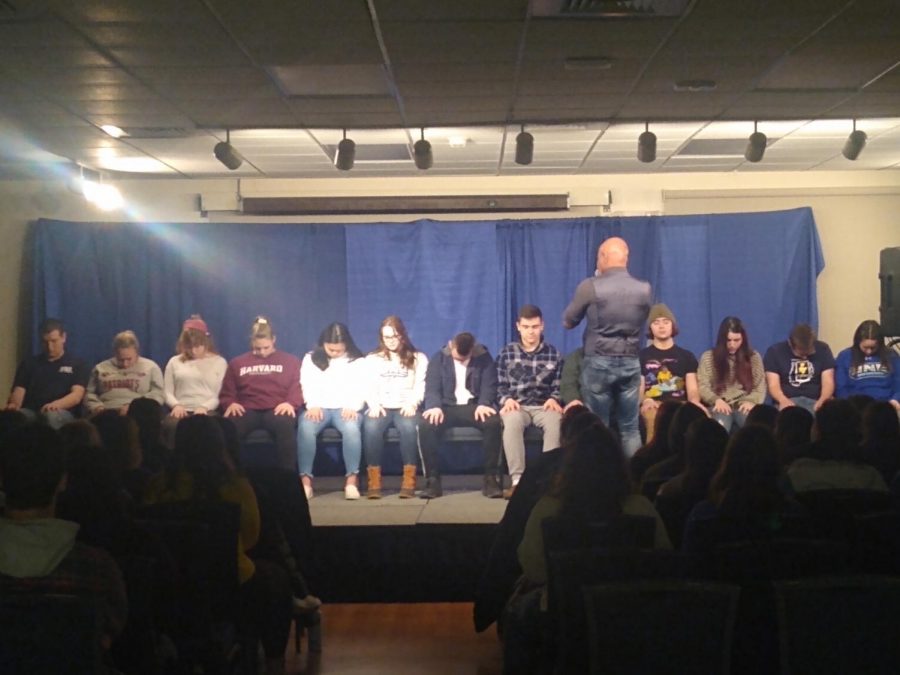 Sailesh standing in front of a row of hypnotized students. 