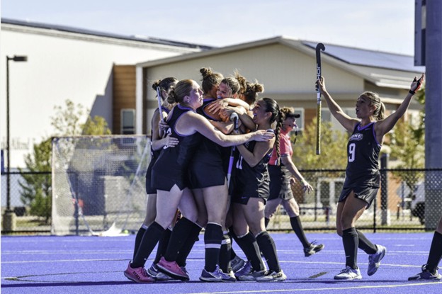 UNE’s Women’s Field Hockey team gathers to celebrate victory.